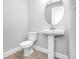 Clean, well-lit bathroom featuring a pedestal sink, round mirror, and modern toilet at 2982 Arranmore Dr, Ormond Beach, FL 32174