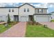 Charming townhome showcasing a brick walkway, manicured landscaping, and a two-car garage under a bright, cloudy sky at 16332 Happy Eagle Dr, Clermont, FL 34714