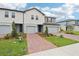 Desirable townhome with brick walkway, two-car garage and well-kept landscaping under a partly cloudy sky at 16332 Happy Eagle Dr, Clermont, FL 34714