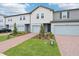 Attractive townhomes featuring brick driveways, two-car garages and landscaped yards on a sunny day with blue skies at 16332 Happy Eagle Dr, Clermont, FL 34714