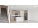 A modern kitchen featuring stainless steel appliances, granite countertops, and stylish gray cabinets sits near the staircase at 16332 Happy Eagle Dr, Clermont, FL 34714
