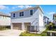 Rear view of a two-story home with a two car garage, paved driveway, and fenced backyard at 8279 Nemours Pkwy, Orlando, FL 32827
