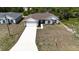 An aerial perspective shows this gray single-story home with a brown roof and a large concrete driveway at 1314 Hillsborough Ct, Poinciana, FL 34759