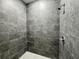 Walk-in shower with gray tiled walls, a shower head, and a non-slip pebble-style floor at 1314 Hillsborough Ct, Poinciana, FL 34759