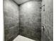 Walk-in shower with gray tiled walls, a shower head, and a non-slip pebble-style floor at 1314 Hillsborough Ct, Poinciana, FL 34759