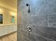 A view into the bathroom showcasing the glass-enclosed shower with a full wall of elegant gray stone-style tiles at 1314 Hillsborough Ct, Poinciana, FL 34759