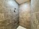 Walk-in shower with gray tiled walls, a shower head, and a non-slip pebble-style floor at 1314 Hillsborough Ct, Poinciana, FL 34759