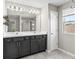 Bathroom featuring double sinks, dark cabinets, a large mirror, and a glass-enclosed shower at 3207 Stratton Cir, Kissimmee, FL 34744