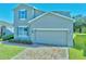 Two-story home showcasing a two car garage, blue shutters, and brick driveway at 3207 Stratton Cir, Kissimmee, FL 34744