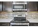 Close up of the kitchen's stainless steel microwave, oven and dark colored cabinets at 3207 Stratton Cir, Kissimmee, FL 34744