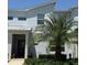 Modern two-story townhome features a red front door, a manicured lawn, and lush landscaping at 8943 Cabot Cliffs Dr, Davenport, FL 33896