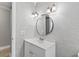 Bright bathroom featuring a round mirror, modern lights, and textured wall details at 510 Cranes Way # 306, Altamonte Springs, FL 32701