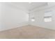 A bright bedroom with neutral carpet, tray ceilings, and two windows at 15542 Sunquat Dr, Winter Garden, FL 34787