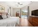 Bright main bedroom with hardwood floors, ceiling fan, dresser, and sliding glass doors to the pool at 807 Grovesmere Loop, Ocoee, FL 34761