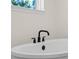 Close up of modern soaking tub with matte black fixtures near window at 347 Mission Rd, Oviedo, FL 32765