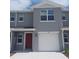 Two-story home with gray siding, red door, a white garage door, and well-maintained front yard at 545 Zinfandel Dr, Holly Hill, FL 32117