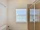 Bathroom shower area with a glass shower door, window, and white tile at 7405 Excitement Dr, Kissimmee, FL 34747
