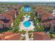 A bird's-eye view of a beautiful community with a pool, palm trees, lush landscaping, and a serene lake with a fountain at 5578 Metrowest Blvd # 101, Orlando, FL 32811