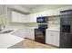 Modern kitchen with white cabinets, black appliances, and tile flooring at 5578 Metrowest Blvd # 101, Orlando, FL 32811