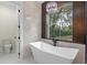 Elegant bathroom featuring a freestanding tub, stylish light fixture, and a serene view of the outdoors at 1003 Oakdale St, Windermere, FL 34786