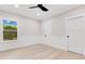 Sunlit bedroom featuring light wood floors, neutral walls, a ceiling fan, and a window with a picturesque view at 1003 Oakdale St, Windermere, FL 34786