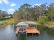 Aerial view of covered boat dock with boat lift, ladders, and clear view of wooded property behind at 1003 Oakdale St, Windermere, FL 34786
