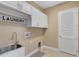 Well-organized laundry room with storage cabinets and a stainless steel sink at 4363 Summer Breeze Way, Kissimmee, FL 34744