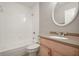 Bathroom featuring tile surround shower and tub combination and vanity with round mirror at 5929 Windhover Dr # A02, Orlando, FL 32819