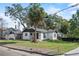 Charming ranch home with white exterior, gray roof and palm tree in front at 400 Raehn St, Orlando, FL 32806