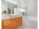Bright bathroom featuring a jacuzzi tub, a decorative vessel sink, and neutral-toned tile floors at 6689 Bell Glade Pl, Sanford, FL 32771