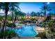 Resort-style pool area with palm trees, a clubhouse, and water features at dusk at 100 Palermo St, Davenport, FL 33897