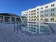 Community pool with a modern building, lounge area, and bright blue sky at 1210 Southstation Pl # 303, Orlando, FL 32809