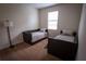 Bedroom with two twin beds, tan carpeting, and a natural light from window at 8979 Azalea Sands Ln, Davenport, FL 33896