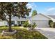 Charming single-story home with a well-maintained front yard, lush tree, and a two-car garage on a sunny day at 3623 Worth Cir, The Villages, FL 32162