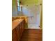 Bright bathroom features a glass-enclosed shower, a vanity with a sink and wooden cabinets, and dark wood-look flooring at 803 Shady Canyon Way, Kissimmee, FL 34759