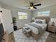Comfortable bedroom with a queen bed, ceiling fan, and natural light from the windows at 603 Conrad Dr, New Smyrna Beach, FL 32168