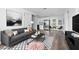 Modern living room featuring a gray sofa, decorative rug, and open access to a compact kitchen at 603 Conrad Dr, New Smyrna Beach, FL 32168