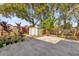 Lush private backyard with mature trees, a patio area, a storage shed, and a wood fence at 4535 Arch St, Orlando, FL 32808