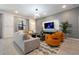 Bright living room with a stylish gray sofa, two orange chairs, and a wall-mounted TV at 6240 Sand Skipper Rd, Orlando, FL 32821