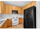 Well-equipped kitchen with oak cabinets, a black refrigerator, and standard white appliances at 13228 Daniels Landing Cir, Winter Garden, FL 34787
