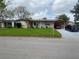 Single-story brick home with a well-maintained lawn and covered carport with 2 cars parked in the driveway at 1222 San Luis Dr, Orlando, FL 32807