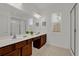 Bathroom showcasing double sinks, a large mirror, wood cabinets, and a glass-enclosed shower at 4571 Cabello Loop, Kissimmee, FL 34746