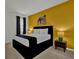 A yellow accent wall complements this bedroom, featuring a king bed, bedside tables, and art at 4571 Cabello Loop, Kissimmee, FL 34746