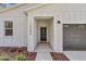 Close-up of the front entrance with stylish details, complemented by landscaping and an attached garage at 12386 Sw 89Th St, Dunnellon, FL 34432