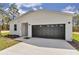 Front elevation of the home highlights a contemporary design with a dark garage door and modern facade at 12386 Sw 89Th St, Dunnellon, FL 34432