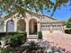 Charming home featuring an arched entryway, two-car garage, and a beautiful brick paver driveway at 15531 Waterleigh Cove Dr, Winter Garden, FL 34787