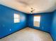 Empty bedroom with bright blue walls, two windows, ceiling fan, and bare floor at 6301 State Road 60 E, Bartow, FL 33830