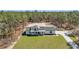 Aerial view of a modern white farmhouse with black trim on a large lot surrounded by trees at 8827 Sw 137Th Ct, Dunnellon, FL 34432