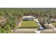 Expansive aerial view of a white farmhouse with black trim surrounded by lush trees and a long driveway at 8827 Sw 137Th Ct, Dunnellon, FL 34432