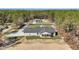 Back aerial view of modern white farmhouse with black trim featuring a covered porch and spacious lot at 8827 Sw 137Th Ct, Dunnellon, FL 34432